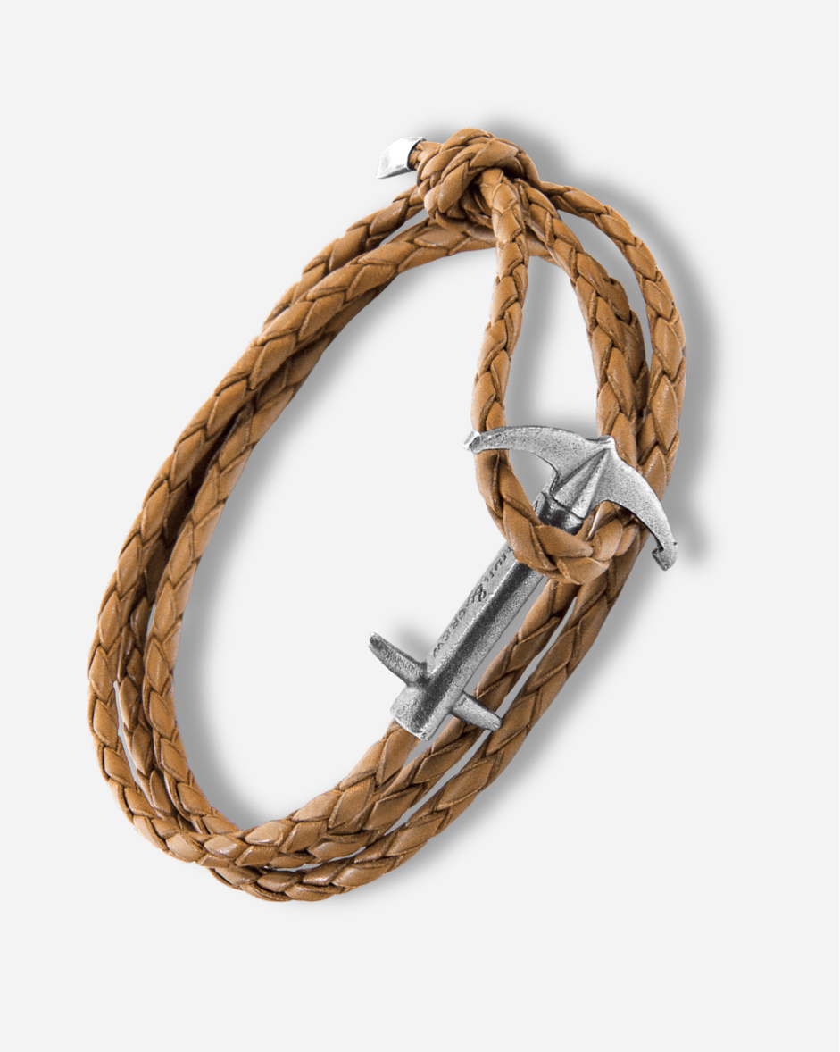 Brown braided leather bracelet with silver anchor charm on a white background