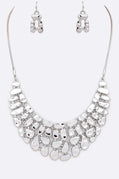 Silver necklace and earrings set on a white background