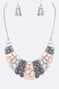 Necklace and earrings set with gray and pink stones on a white background