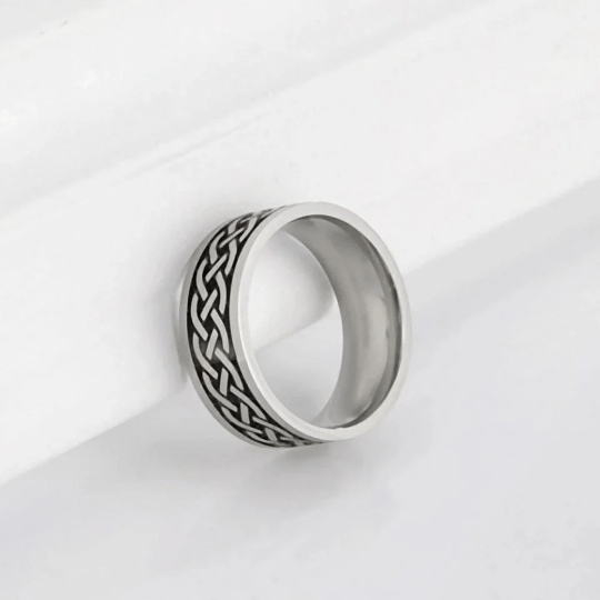 Silver ring with intricate design on a white background