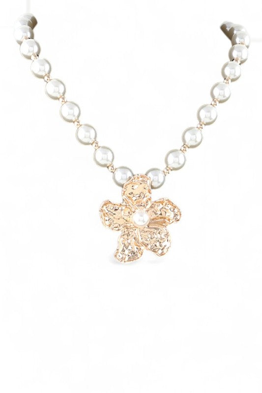 Necklace with pearl beads and a gold flower pendant on a white background