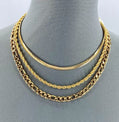 Three gold chains on a mannequin neck against a gray background