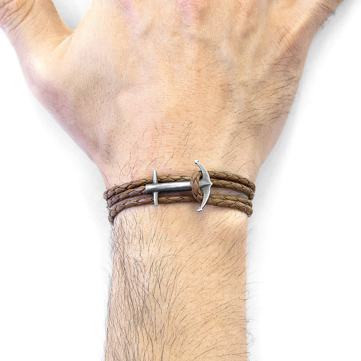 Brown leather bracelet with silver anchor charm on a wrist against a white background