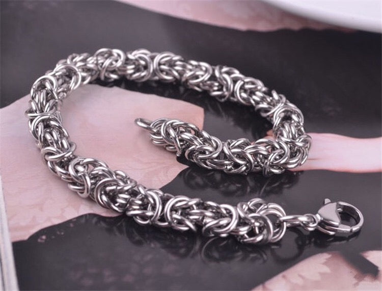 Silver chain bracelet on a hand against a dark background