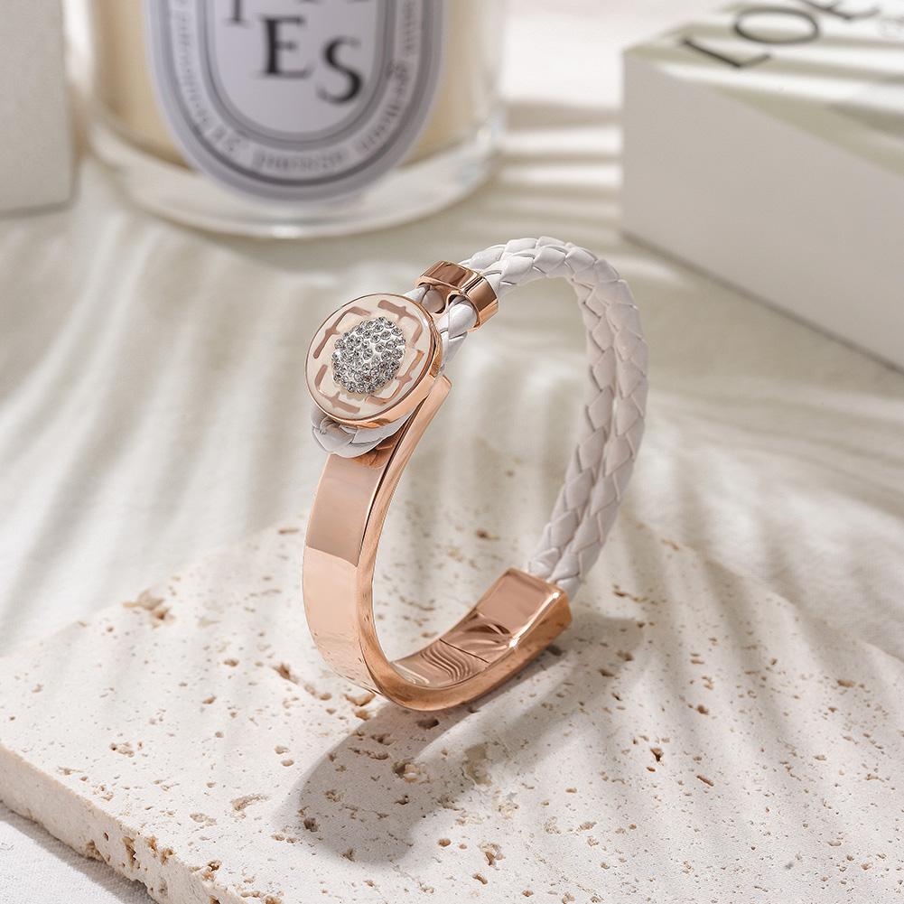 Rose gold bracelet with white leather strap on a textured surface