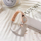Rose gold bracelet with white braided strap on a light surface with 'Loewe' branding.