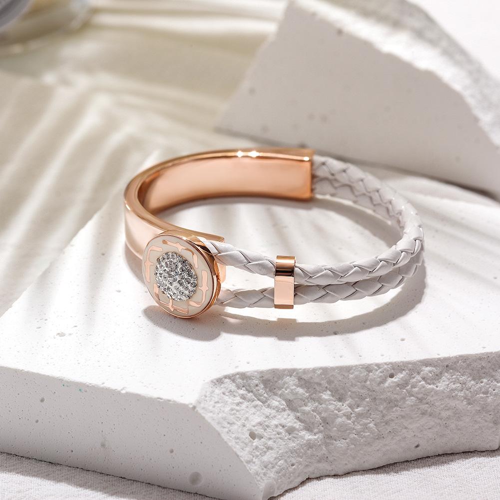 Rose gold and white braided bracelet on a textured surface