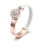 Rose gold ring with a white braided band on a white background