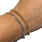 Two chain bracelets, one gold and one silver, on a person's wrist against a white background.