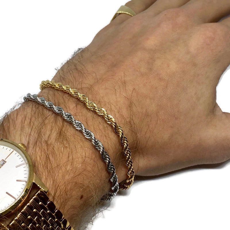 Hand wearing a gold watch and two bracelets on a white background