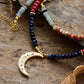 Necklace with beaded chain and gold crescent moon pendant on a wooden surface