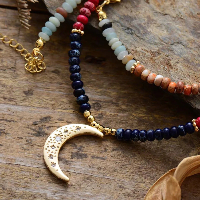 Necklace with beaded chain and gold crescent moon pendant on a wooden surface