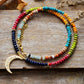 Colorful beaded necklace with a gold crescent moon pendant on a wooden surface