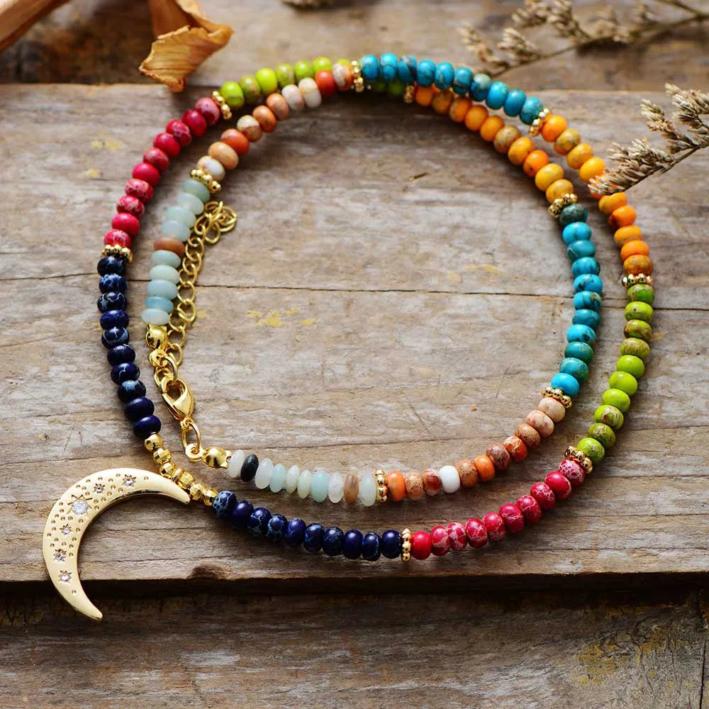 Colorful beaded necklace with a gold crescent moon pendant on a wooden surface