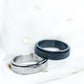 Two rings, one black and one silver with glittery texture, on a white background.