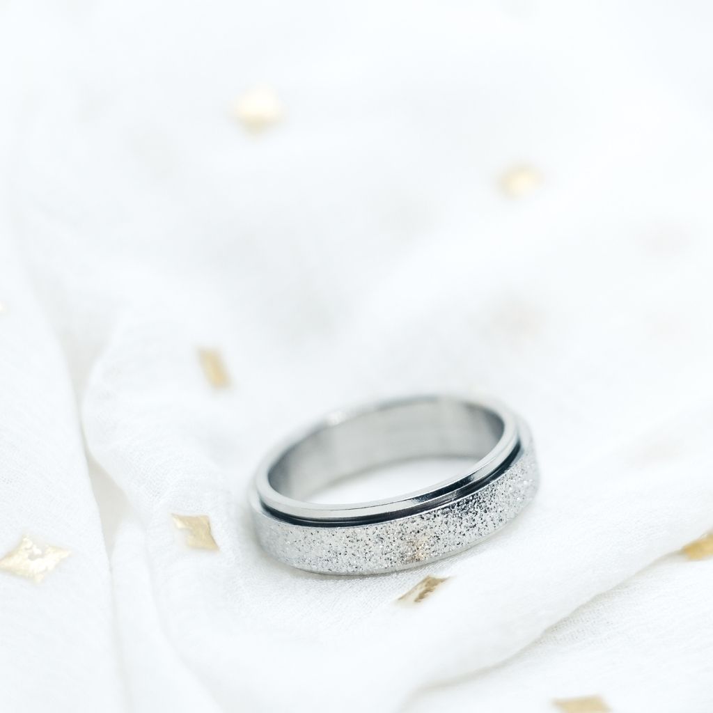 Silver ring with glittery band on a white background