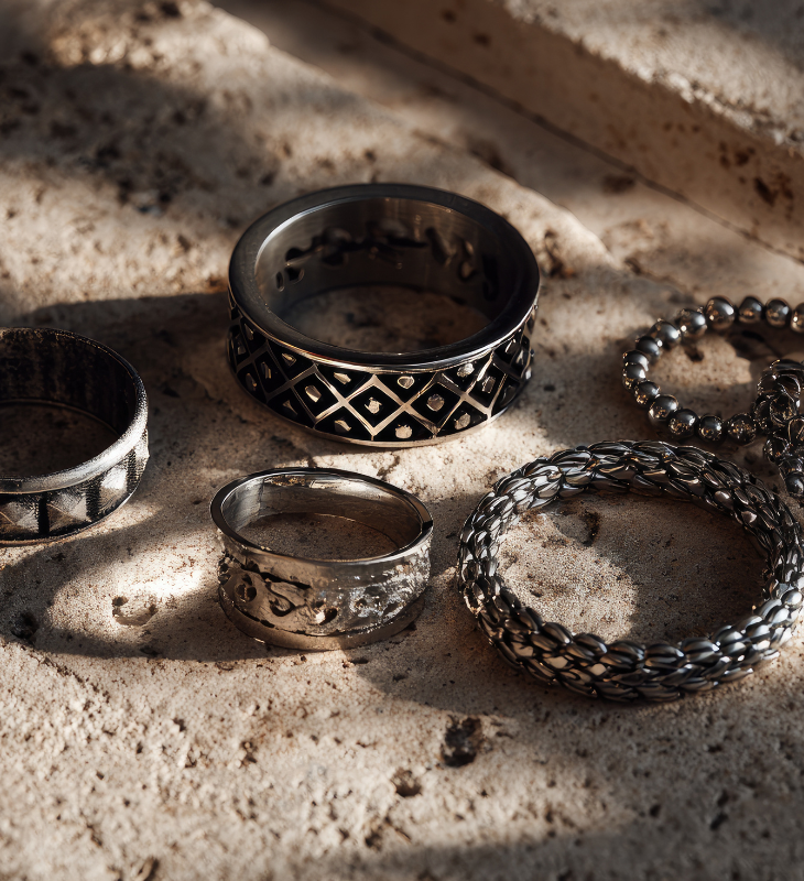 Silver rings and bracelets on a textured surface