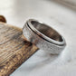 Silver ring with textured design on a wooden surface