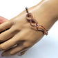 Rose gold bracelet on a mannequin hand against a white background