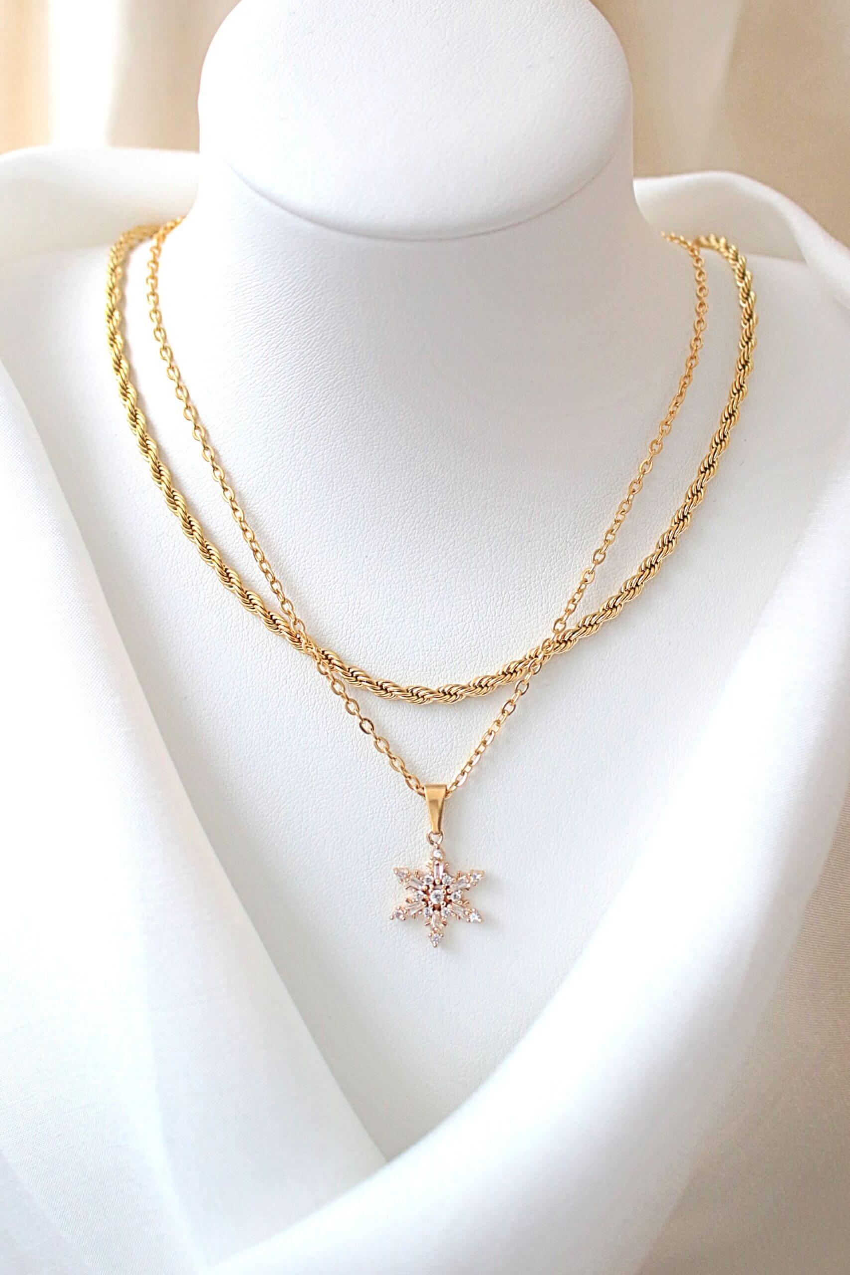 Two gold necklaces on a mannequin bust with a plain background