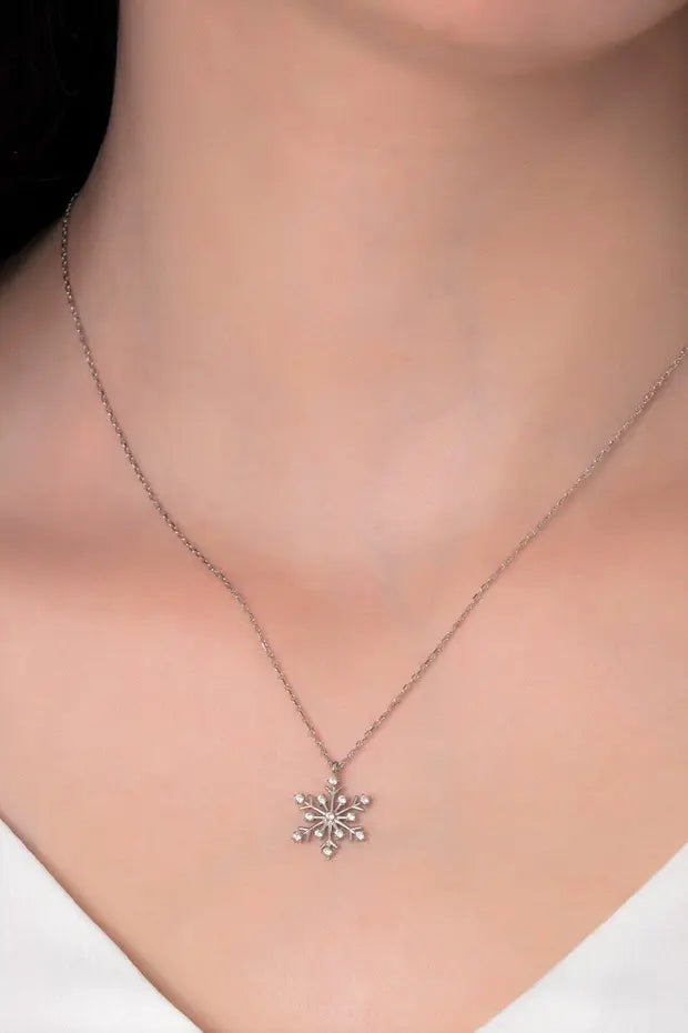 Snowflake pendant necklace on a person wearing a white shirt