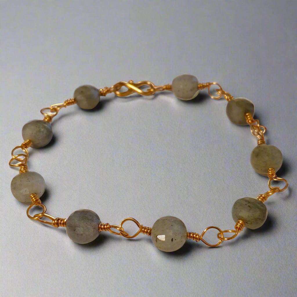 Bracelet with gold wire and beige beads on a light gray background