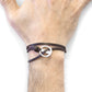 Brown leather bracelet with a silver clasp on a wrist against a white background