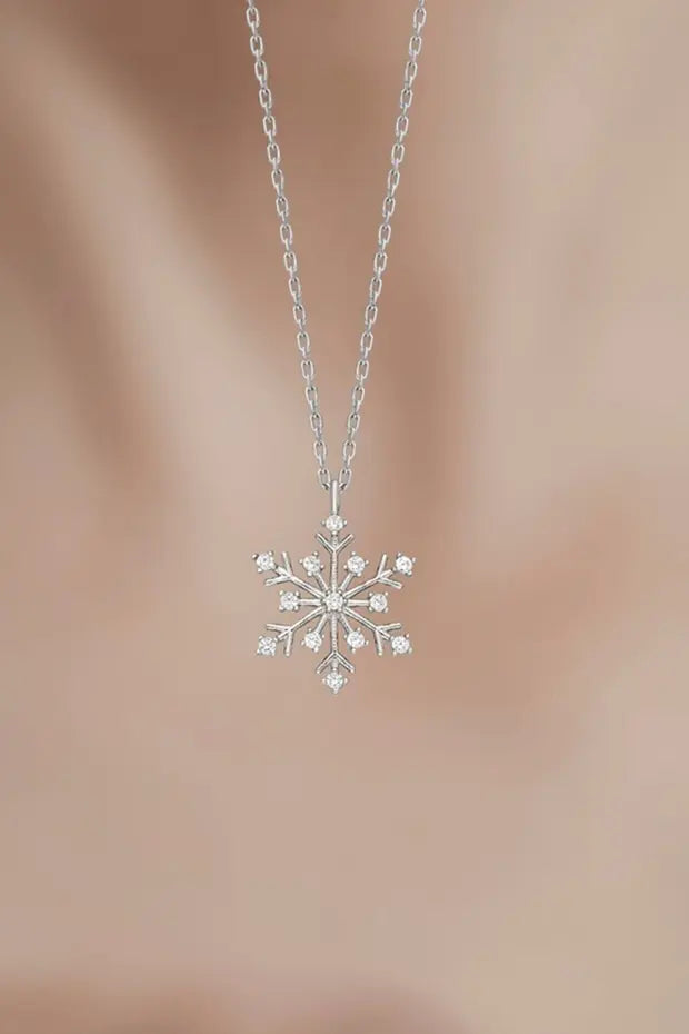 Silver snowflake pendant necklace on a blurred background