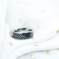 Silver ring with Celtic knot design on a white background