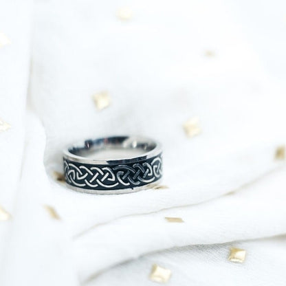 Silver ring with Celtic knot design on a white background
