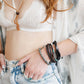 Person wearing a white lace bralette and denim shorts with bracelets on a blurred background